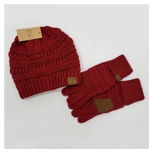 May include: Red knit beanie hat and matching gloves with a brown leather patch and the text "CC" on the hat and gloves.