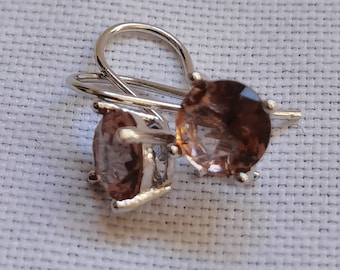 May include: A pair of silver earrings with brown gemstone accents. The earrings have a simple, elegant design.