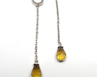 May include: A pair of silver dangle earrings with a teardrop-shaped amber gemstone at the end of each chain.
