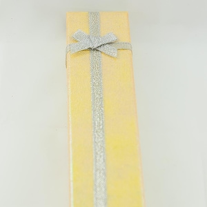 May include: A yellow gift box with a silver ribbon and bow.