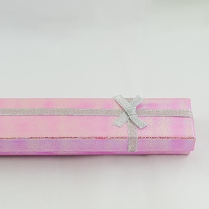 May include: A pink gift box with a silver ribbon and bow. The box is made of a shimmery material and has a subtle iridescent sheen.