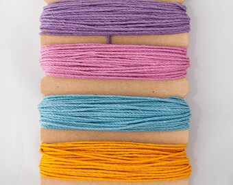 May include: Four spools of 100% hemp crafter's cord in purple, pink, blue, and yellow. The spools are labeled "True Hemp" and "Hemptique" with the text "A Natural Product of the Earth".