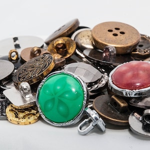 Puede incluir: Una colección de botones surtidos en varios colores, formas y tamaños. Los botones están hechos de metal, plástico y vidrio. Algunos botones tienen un diseño decorativo, mientras que otros son lisos. Los botones son una mezcla de estilos vintage y modernos.