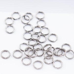 May include: A pile of silver jump rings, a type of metal ring used for jewelry making and crafting.
