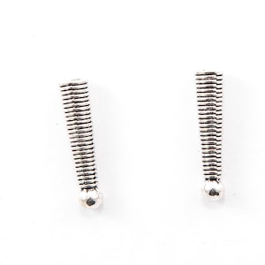 May include: Two silver-colored, textured metal components, each with a cylindrical shape and a rounded base. The components have a series of horizontal lines along their length, creating a ribbed appearance. The background is plain white.