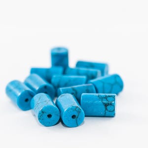 May include: A pile of turquoise blue cylindrical beads, some with a mottled pattern, on a white background.