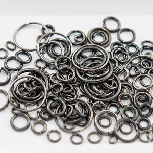 Op de afbeelding: Een grote verzameling zilveren springringen in verschillende maten. De ringen zijn gemaakt van metaal en perfect voor het maken van sieraden of knutselen.