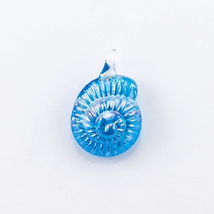 May include: A blue glass pendant shaped like a seashell with iridescent details.