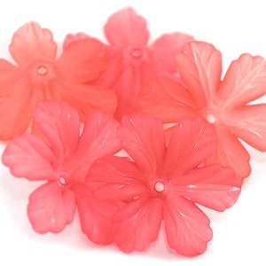 May include: A group of six coral pink plastic flower beads. Each bead has five petals and a hole in the center.