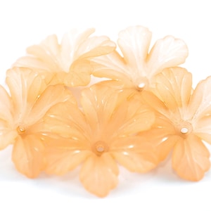 May include: Five peach-colored plastic flower beads with five petals each. The beads have a hole in the center for stringing.