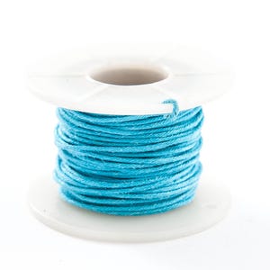 May include: A spool of bright turquoise thread. The thread is tightly wound around a white plastic spool. The image is a close-up shot against a white background, highlighting the vibrant color and texture of the thread.