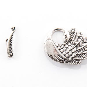 May include: A silver-toned metal clasp set featuring a peacock design. The clasp includes a decorative peacock with a detailed tail and a separate bar component. The set is designed for jewelry making or crafting.
