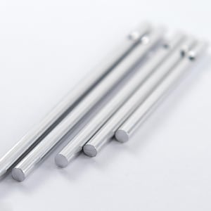 Pode incluir: Quatro hastes de metal prateadas de comprimentos diferentes, dispostas em um padrão escalonado em uma superfície branca.