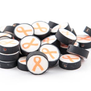 May include: A pile of black and white round beads with an orange ribbon design.