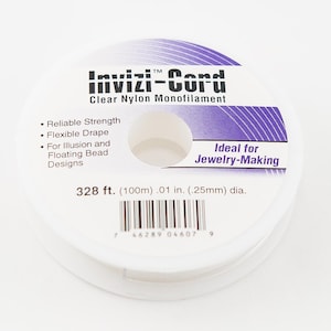 May include: A spool of clear nylon monofilament called "Invizi-Cord" for jewelry making. The spool is white with purple text and a barcode. It is 328 feet (100 meters) long and 0.01 inches (0.25 millimeters) in diameter.