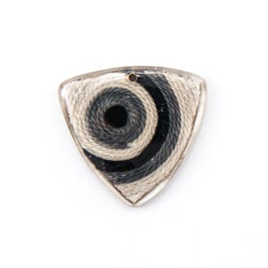May include: A triangular pendant with a silver-colored border. The pendant features a spiral design in shades of gray and black, with a small hole at the top for a chain or cord. The design is reminiscent of a guitar pick.