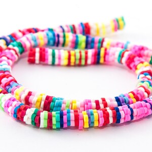 May include: A necklace composed of brightly coloured, flat, round beads in pink, red, yellow, green, blue, and white. The beads are strung together, forming a circular shape, with some strands visible.