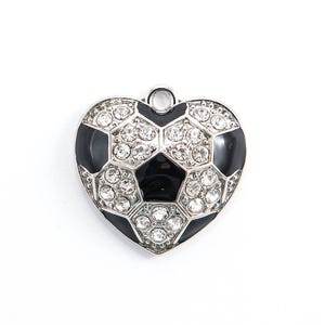 Puede incluir: Un amuleto de plata en forma de corazón con un diseño de balón de fútbol blanco y negro. El balón de fútbol está cubierto de diamantes de imitación transparentes.