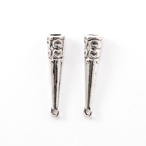 May include: Two silver-colored, cone-shaped jewelry findings. The top portion of each finding has a decorative, circular pattern. Each finding has a small loop at the bottom. The findings are on a white background.