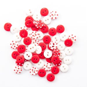 May include: A collection of red, white, and red-and-white polka dot buttons. The buttons are round with two holes and are scattered on a white background. The buttons are in various sizes.