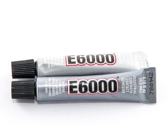 Op de afbeelding: Twee tubes E6000 industriële contactlijm. De tubes zijn zilverkleurig met zwarte doppen en rode en witte tekst. Eén tube bevat 5,3 ml.
