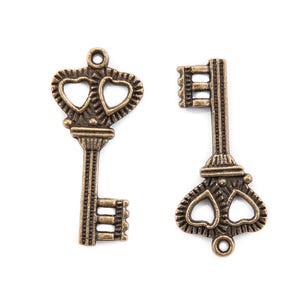May include: Two antique-style keys with heart-shaped cutouts. The keys are made of metal and have a bronze finish.