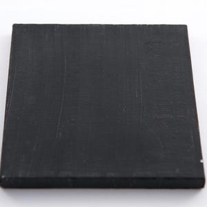 Puede incluir: Una pintura de lienzo cuadrado negro con una superficie texturizada.
