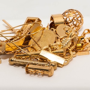 May include: A collection of gold-toned jewellery findings, including earring backs, clasps, and chain links.
