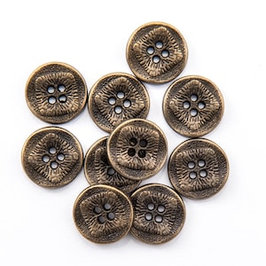 May include: A collection of antique bronze-colored buttons. Each button is round with a textured floral design and four holes for sewing. The buttons are arranged on a white background, showcasing their intricate details.