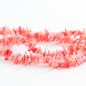 Op de afbeelding: Een streng roze koraal kralen, elke kraal is een kleine, onregelmatige tak van koraal.