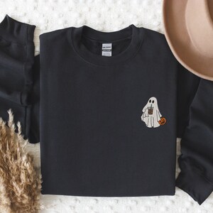 May include: Black sweatshirt with a white ghost holding a cup of coffee and a small orange pumpkin.