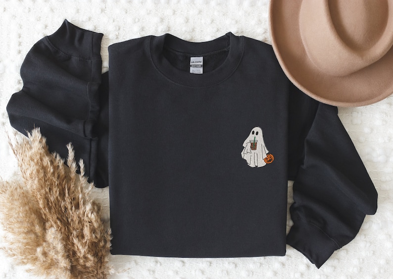 May include: Black sweatshirt with a white ghost holding a cup of coffee and a small orange pumpkin.