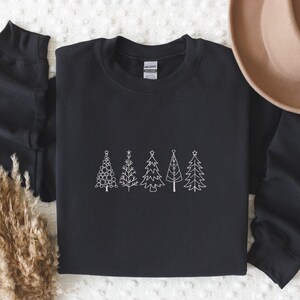 May include: Black sweatshirt featuring a white outline of five Christmas trees. The trees are decorated with baubles and stars.