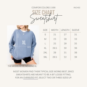 Puede incluir: Una sudadera azul claro con una etiqueta de talla XL, mostrada con una tabla de tallas. La tabla enumera las tallas S a 3XL, con medidas en pulgadas para el ancho, largo y manga. El texto dice "COMFOR COLORS 1566" y "Sweatshirt".