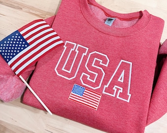 May include: Red sweatshirt with a white "USA" graphic and a small American flag embroidered on the front.