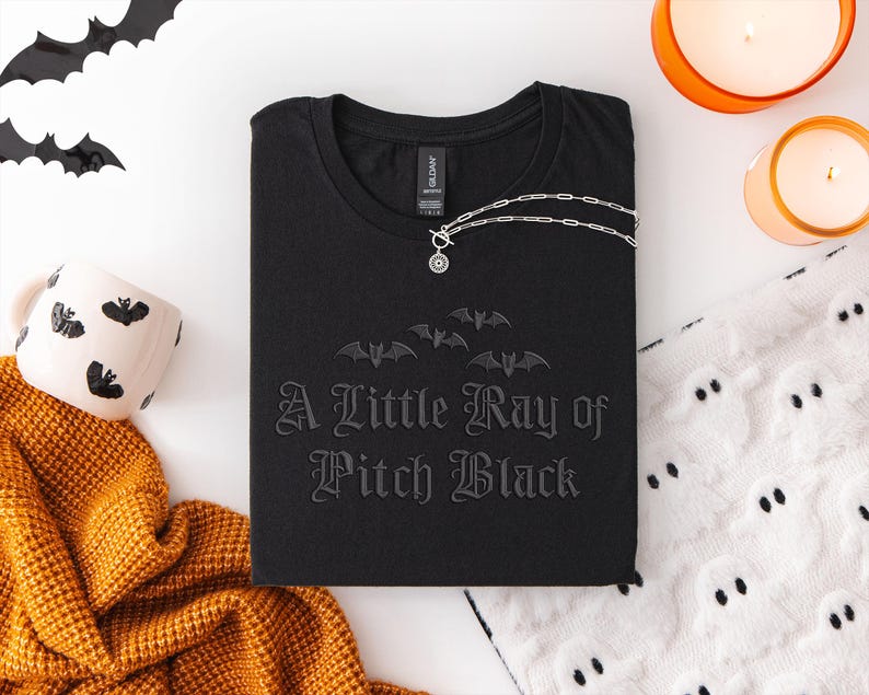 Spooky embroidered Halloween t-shirt: “A Little Ray of Pitch Black” with bats. Soft, comfy Gildan tee in dark gray or black