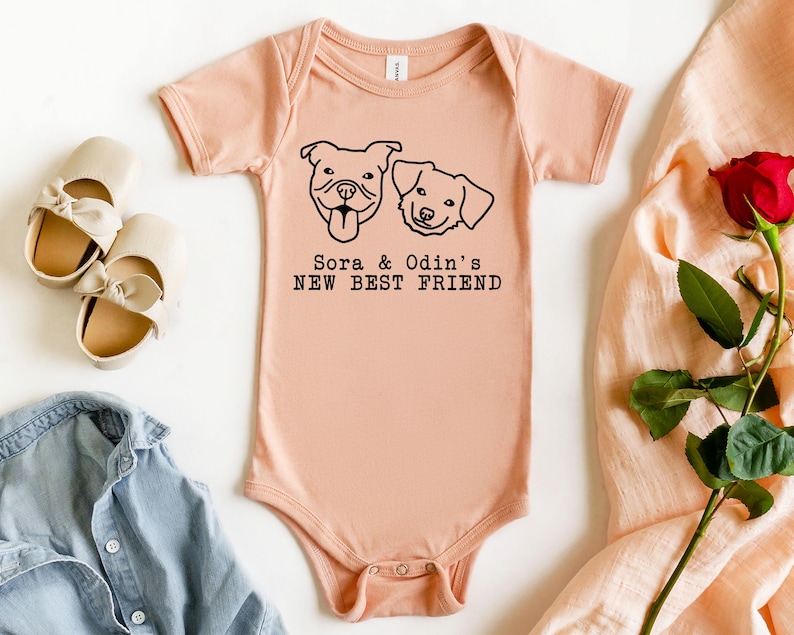 a baby onesie with a graphic of two dogs, a pink onesie, a pair of white shoes, a red rose, and a denim shirt, all arranged on a white background.
