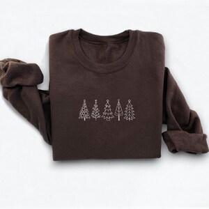May include: A brown sweatshirt with a white outline of five Christmas trees on the front.