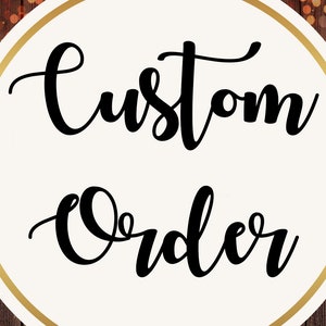 Puede incluir: Un círculo blanco con un contorno dorado, sobre un fondo de madera marrón. El círculo contiene el texto "Custom Order" en fuente cursiva negra.