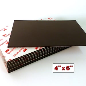 Pode incluir: Uma pilha de folhas magnéticas retangulares castanho-escuras, medindo cada uma 4 polegadas por 6 polegadas. A superfície superior é castanho-escura, enquanto o verso apresenta um adesivo branco com o logótipo vermelho 3M Electronics impresso.