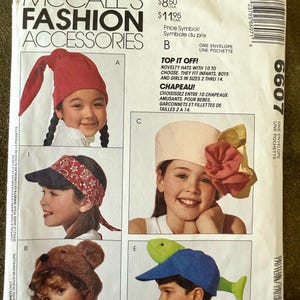 May include: McCall's Fashion Accessories pattern envelope featuring children's hats. The envelope includes images of various hat styles, including a red elf hat, a bandana visor, a bear hat, a floral hat, and a blue cap with a green fish. Text on the envelope reads "Top It Off!" and "Chapeau!"