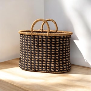 May include: A black and brown woven oval basket with two handles. The basket is made of natural materials and has a checkered pattern.