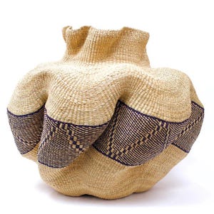 May include: A large, woven basket with a unique, organic shape. The basket is made of natural fibers and has a brown and purple striped pattern.