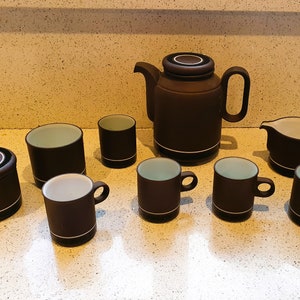 Könnte beinhalten: Ein braunes und schwarzes Keramik-Tee-Set mit einer Teekanne, einer Milchkännchen, einer Zuckerdose und sechs Tassen.