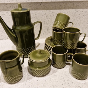 Może przedstawiać: Zestaw do herbaty z zielonej ceramiki z czajnikiem, dzbankiem na śmietanę, cukiernicą i sześcioma filiżankami i spodkami. Zestaw ma geometryczny wzór.