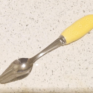 May include: A yellow lemon zester with a stainless steel handle. The zester has a serrated edge and a spoon-like shape.
