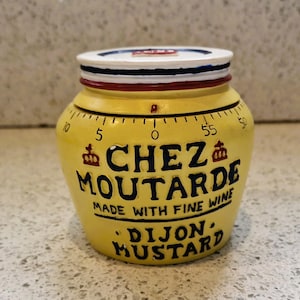 May include: A yellow ceramic Dijon mustard pot with a white, blue, and red lid. The pot features the text "CHEZ MOUTARDE" and "DIJON MUSTARD" in black lettering. A timer scale is printed around the pot.
