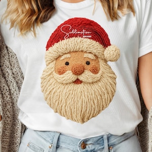 May include: White t-shirt featuring a detailed Santa Claus face design. The Santa Claus face has a red hat, a long beige beard, and a smiling expression. The word "Sublimation" is written in red script above the Santa Claus face.