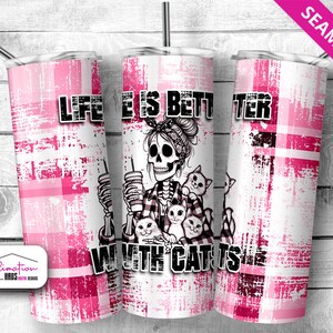 May include: A pink and white tumbler with a skull and cats design. The tumbler has the text "Life is better with cats" on it.