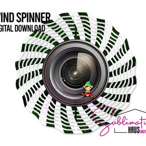 Puede incluir: Una descarga digital para un diseño de molinillo de viento con un patrón de rayas blancas y negras con acentos verdes. El diseño tiene la forma de una lente de cámara con una pequeña figura de elfo en su interior.